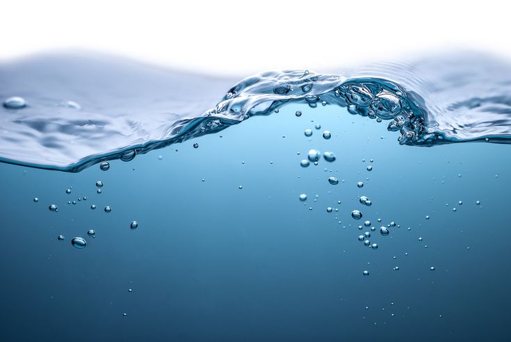 Crystal clear purified blue water surface with rising bubbles